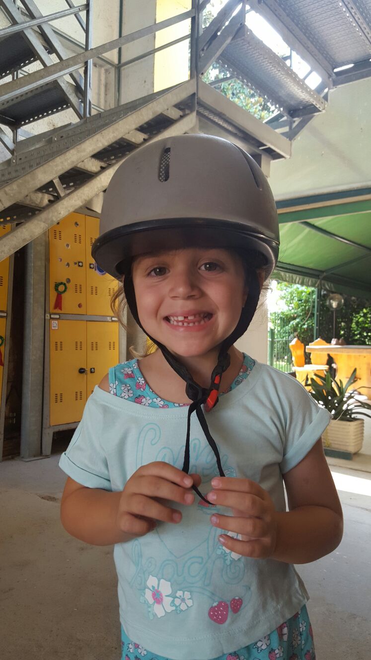 Una giovane allieva sorridente con il casco da equitazione